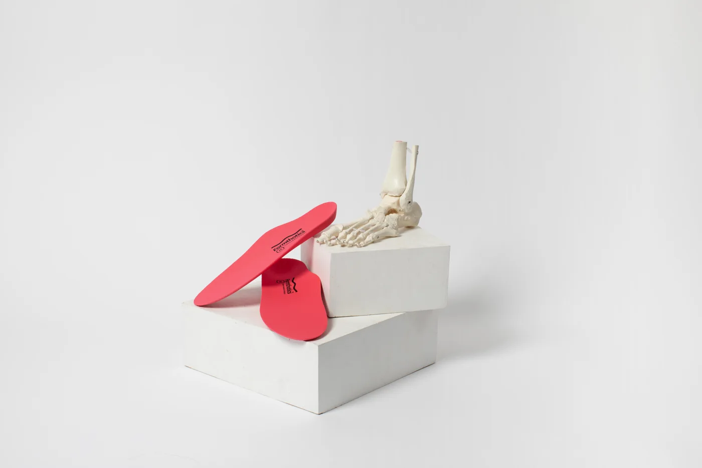 Formthotics orthotics shown beside a model of the foot